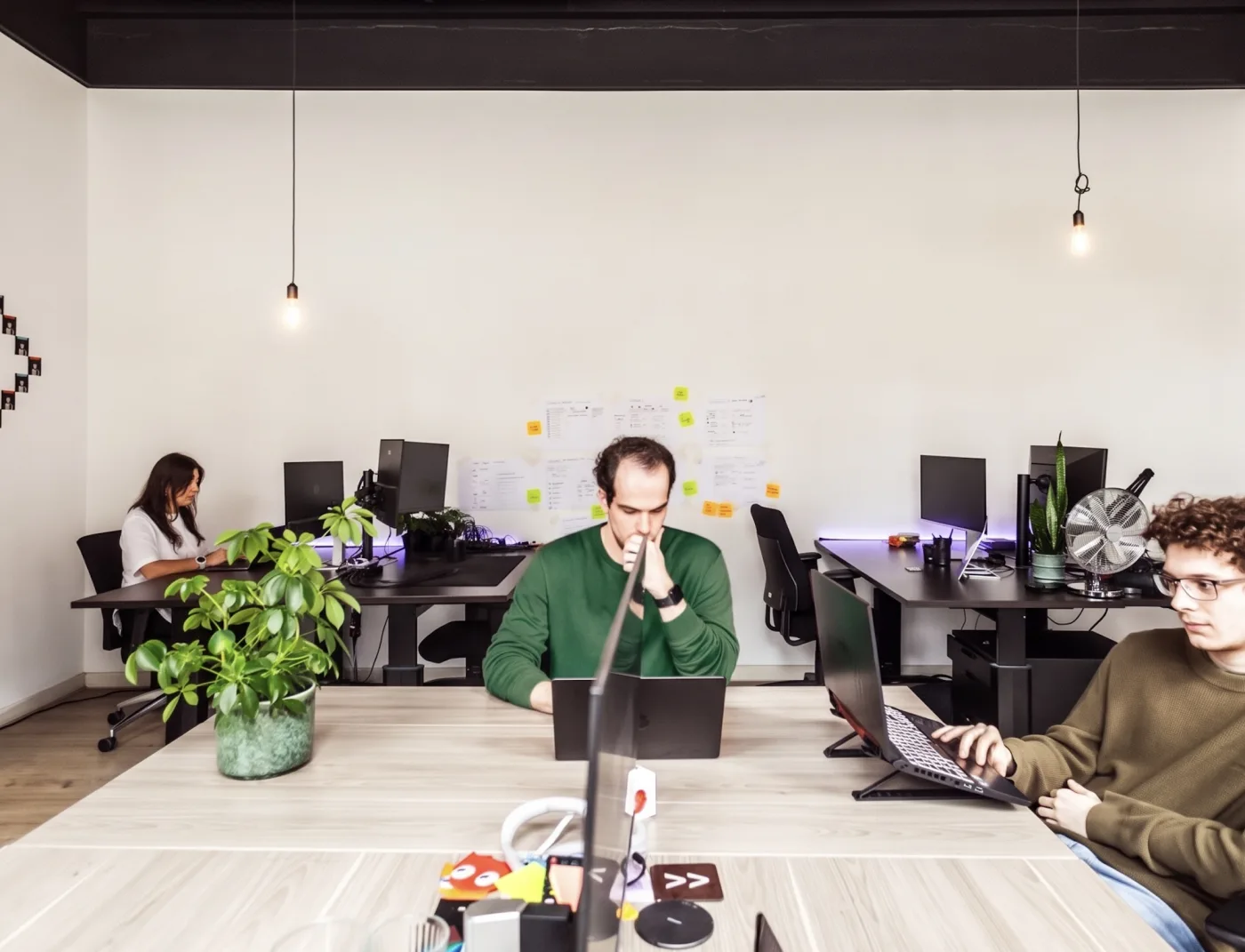 The Future Ready studio in Amsterdam: three people working at their desks, with a wall of notes behind them